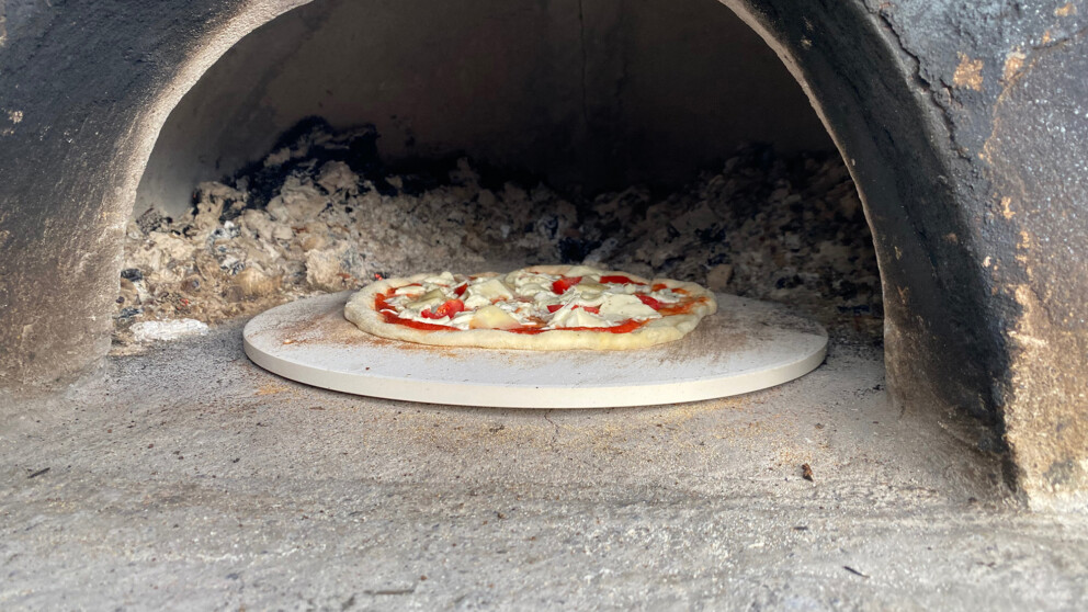 Pizza auf dem Pizzastein im Pizzaofen.