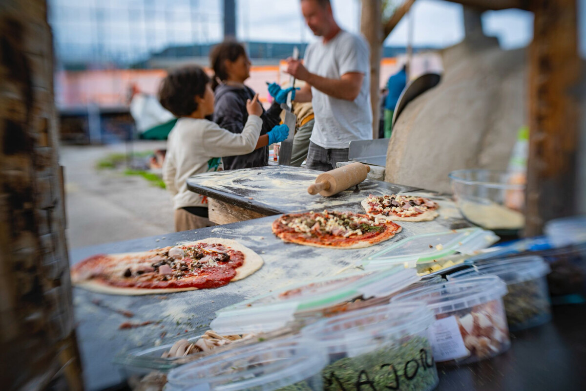 Belegte Pizzas warten auf der Pizzatheke, dass sie im Ofen gebacken werden.