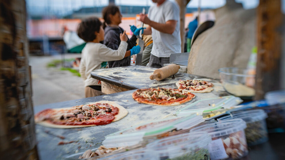 Belegte Pizzas warten auf der Pizzatheke, dass sie im Ofen gebacken werden.
